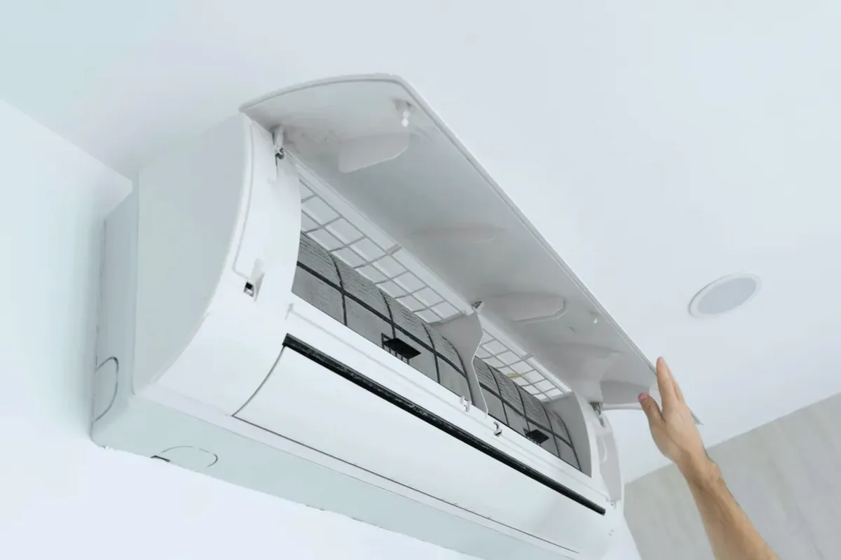 Hand opening the cover of a wall-mounted ductless air conditioner